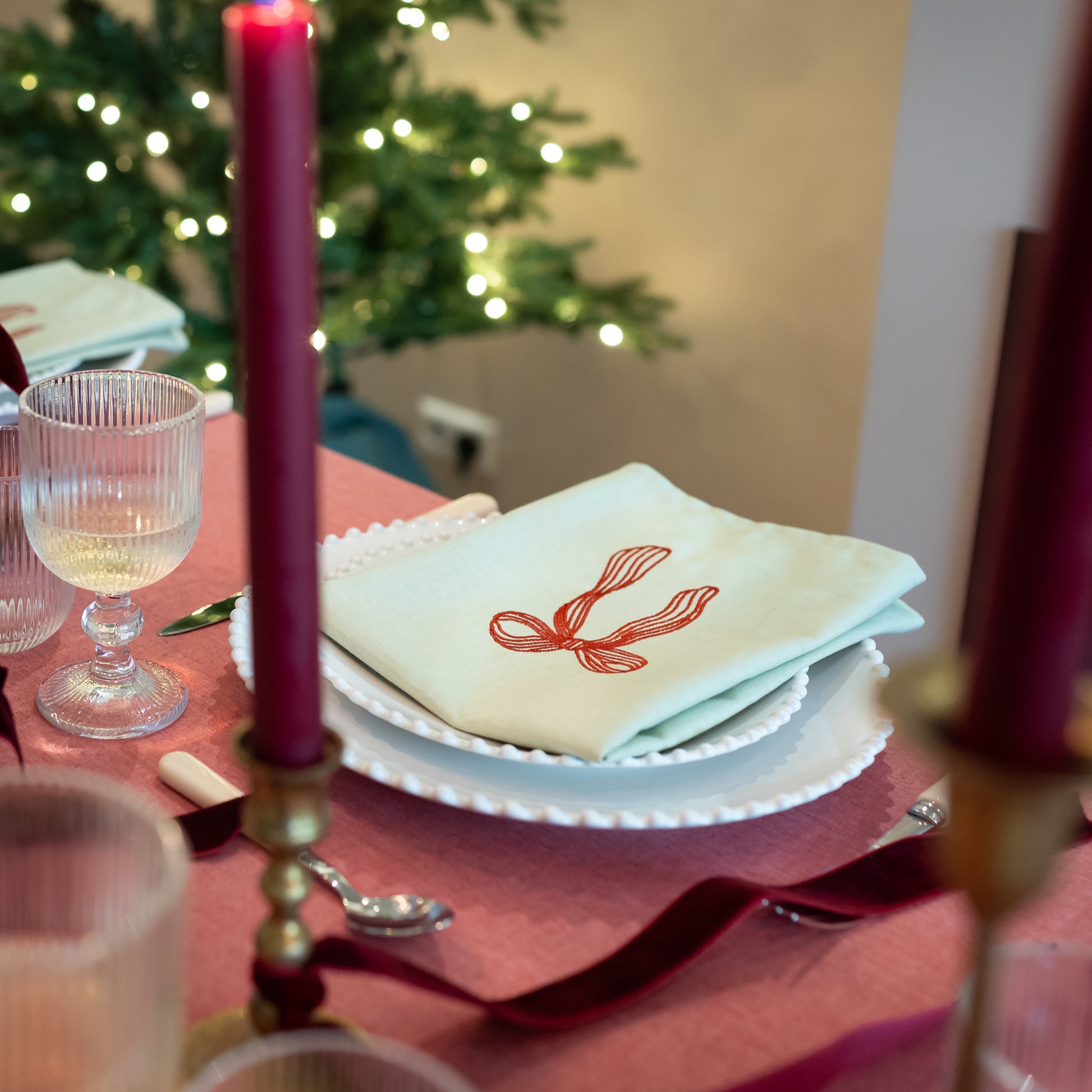 Tafelkleed Rood Gedekt Met Costa Nova Borden En Lichtgroene Servet met Strikborduursel
